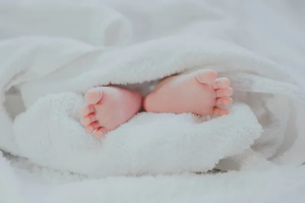 Baby feet poking out of furry white blanket.