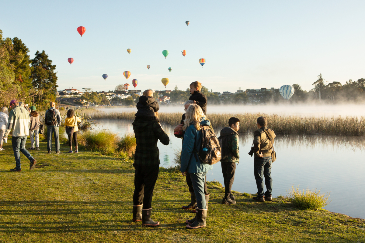 Family looking at the hot air balloons floating over Lake Rotoroa/Hamilton Lake