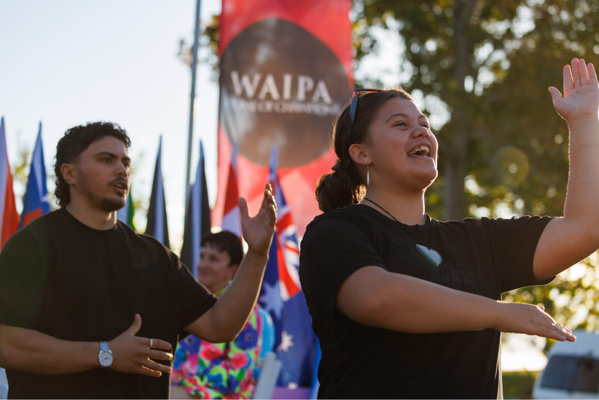 Kapa Haka performance with Waipa - Home of Champions flag blurred in the background