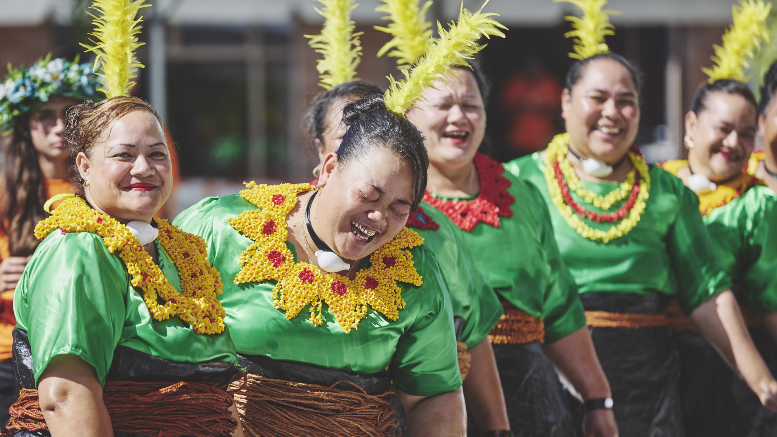 Pasifika performers in costume laughing and smiling