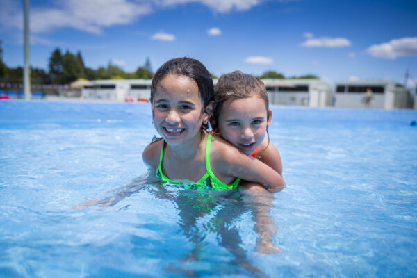 Two young girls in a swimming pool.