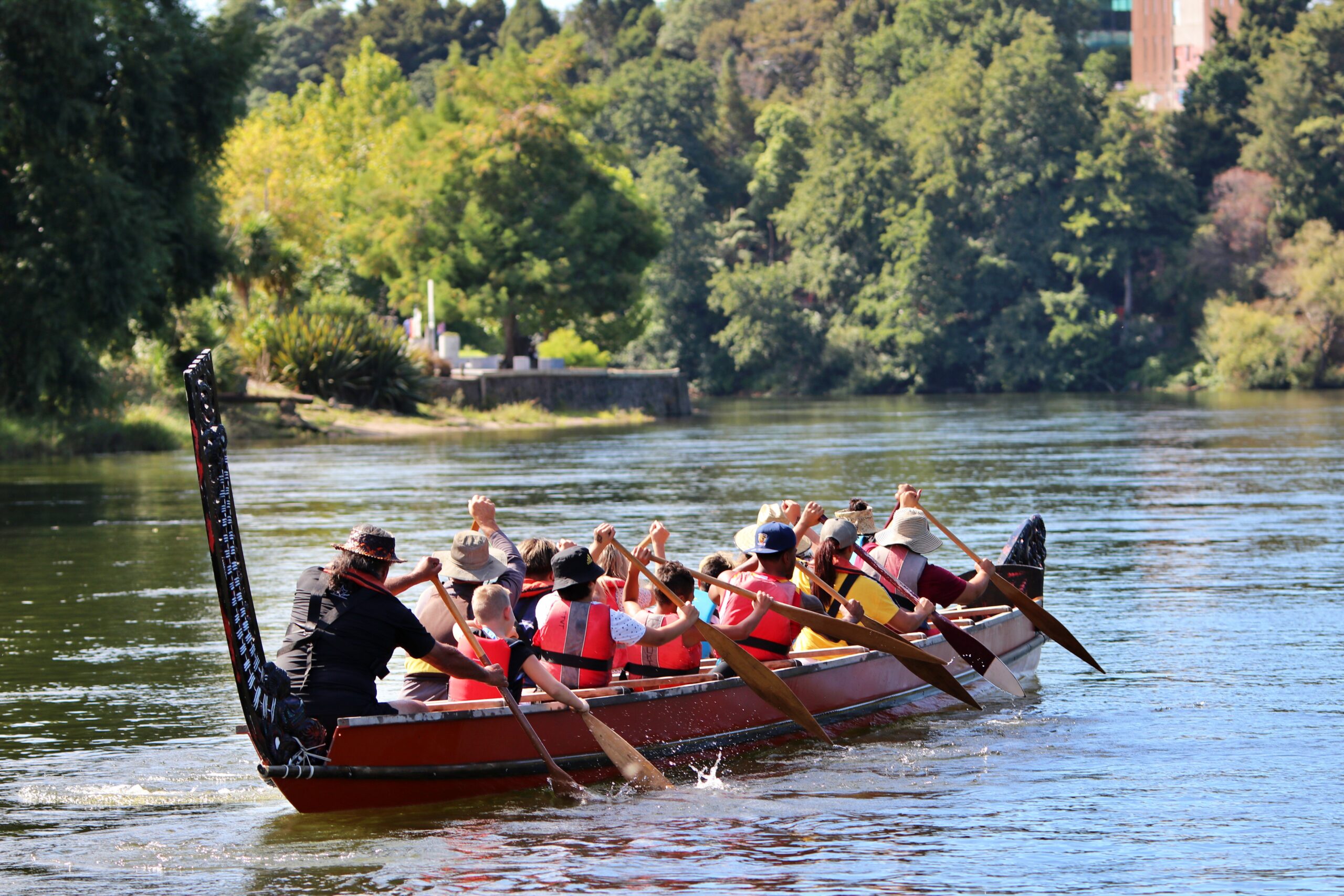 Group of young people paddling down the Waikato river in a waka teetee