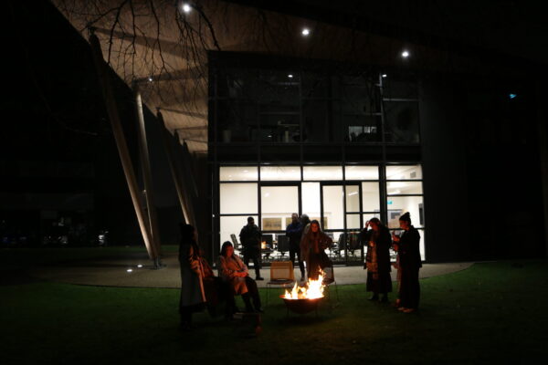 Trust Waikato staff standing around a fire pit outside the building in the dark.
